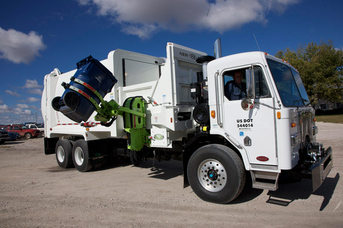 white garbage truck lifting a blue collection bin